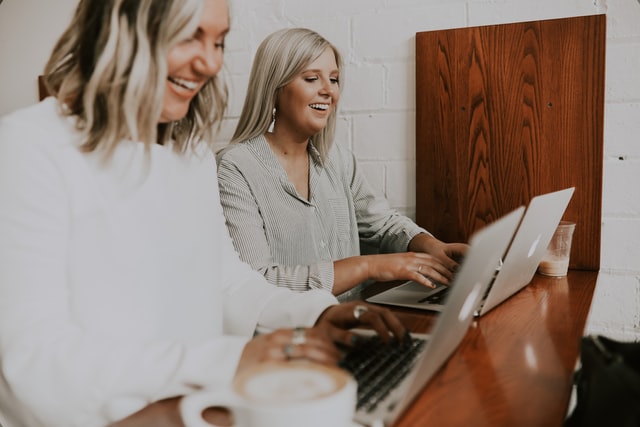 two white women working on laptops